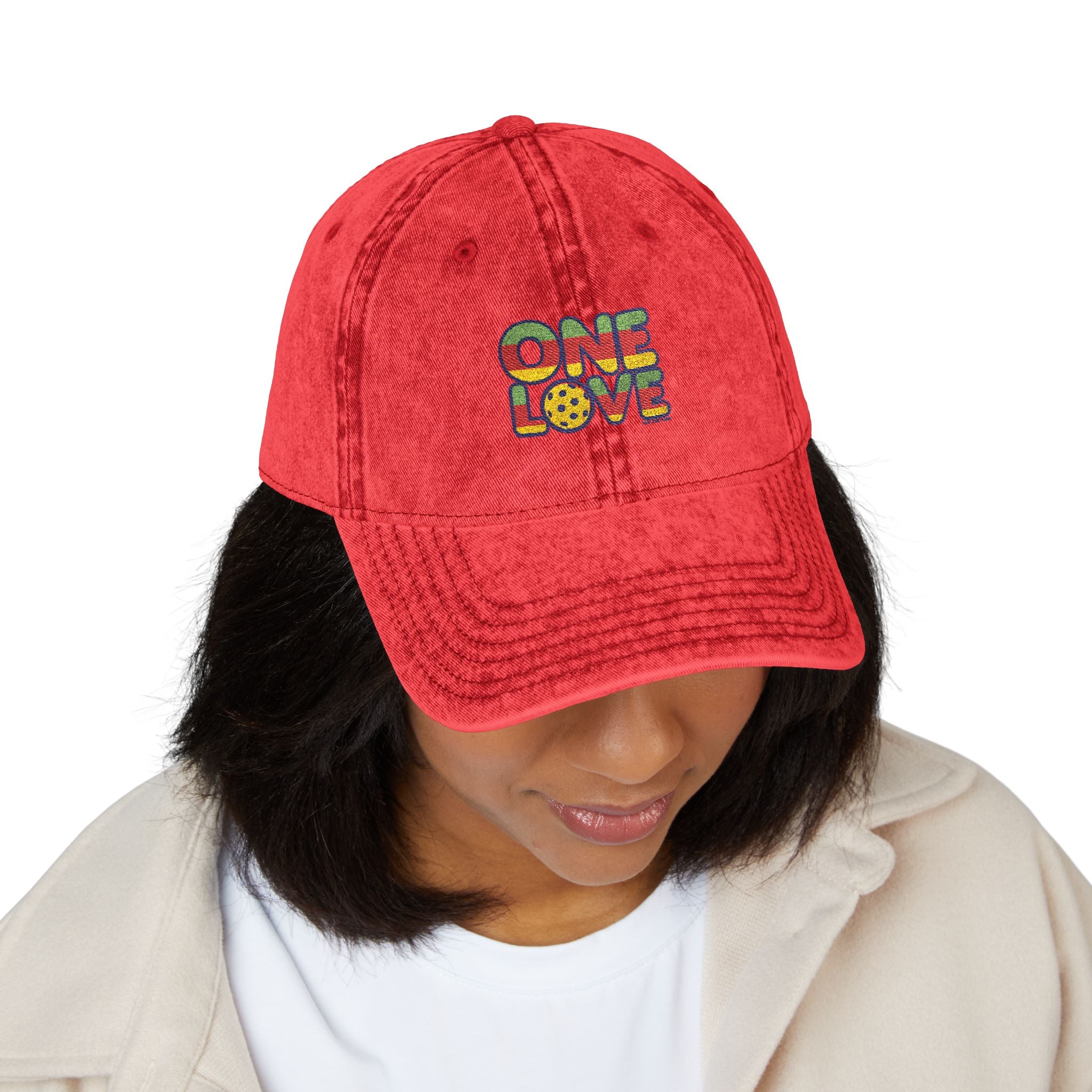 Red cap with 'ONE LOVE' text worn by a person on a white background